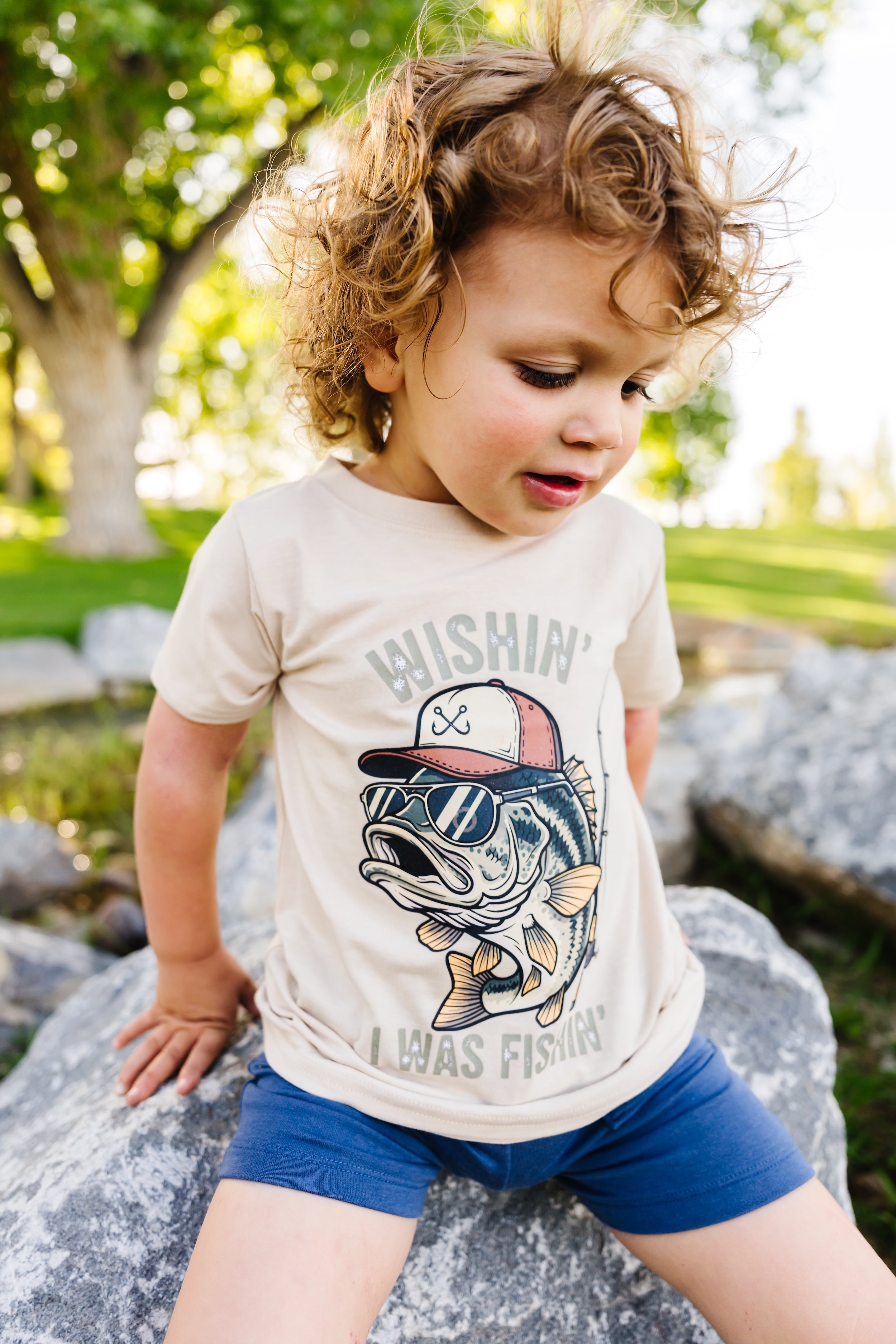 Child wearing a fishing t-shirt with a graphic design outdoors